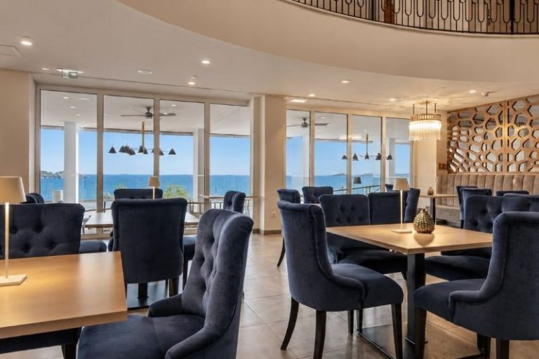 Elegant dining area with blue upholstered chairs, contemporary lighting and panoramic windows at Vista Restaurant Dubrovnik